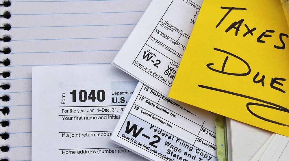 Tax return forms and wage statements with note Taxes Due.