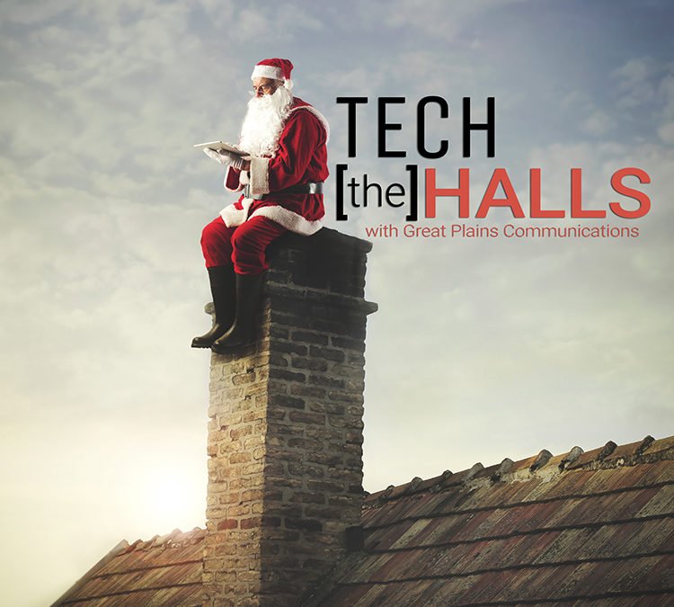 Old man dressed as santa claus sitting on top of a chimney using his tablet