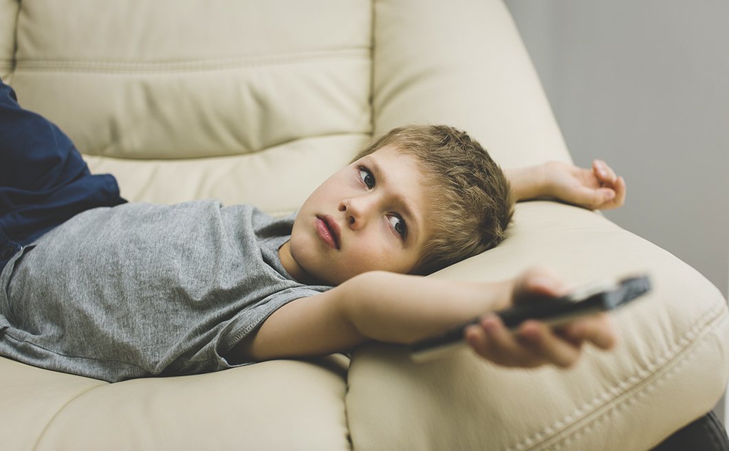 Close-up of little boy controlling remote control on couch