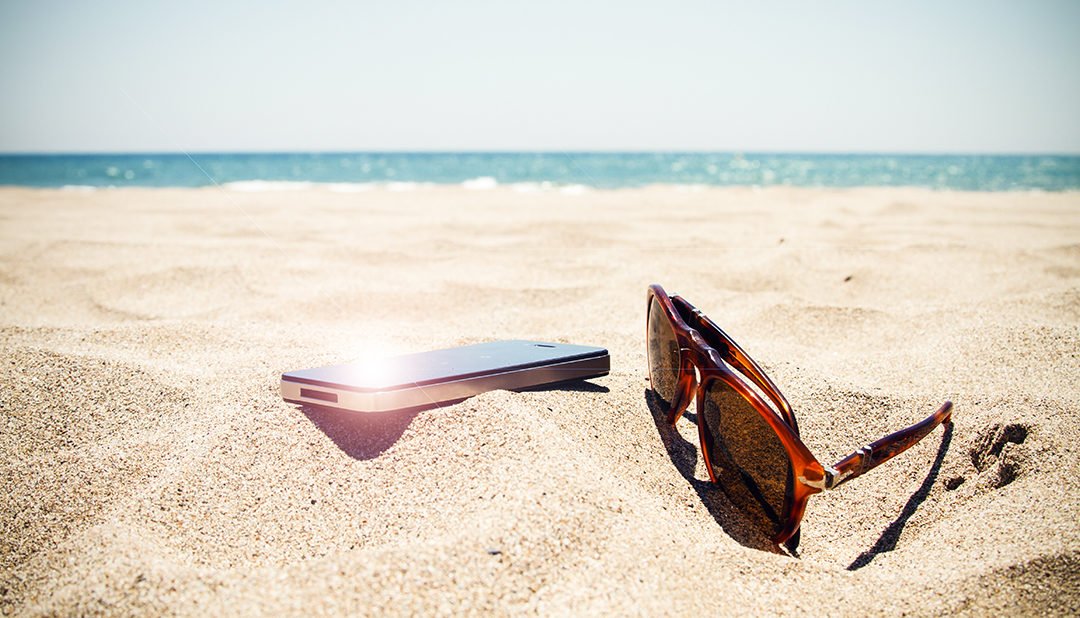 Smartphone and sunglasses on the beach