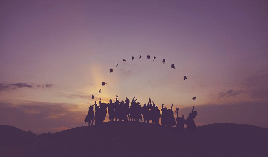graduates throwing hats into the sunset
