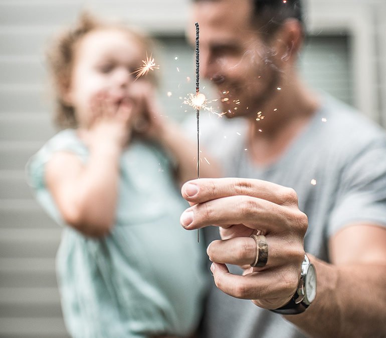 man holding daughter and sparkler