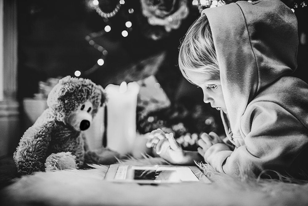 Young child watching tablet by Christmas tree